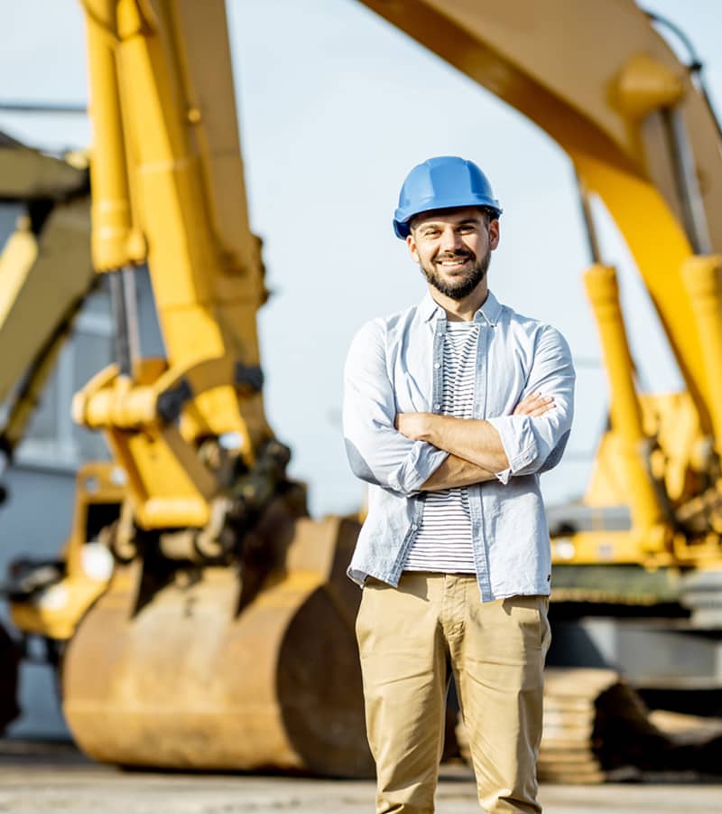 builder standing on jobsite with heavy machinery in the background